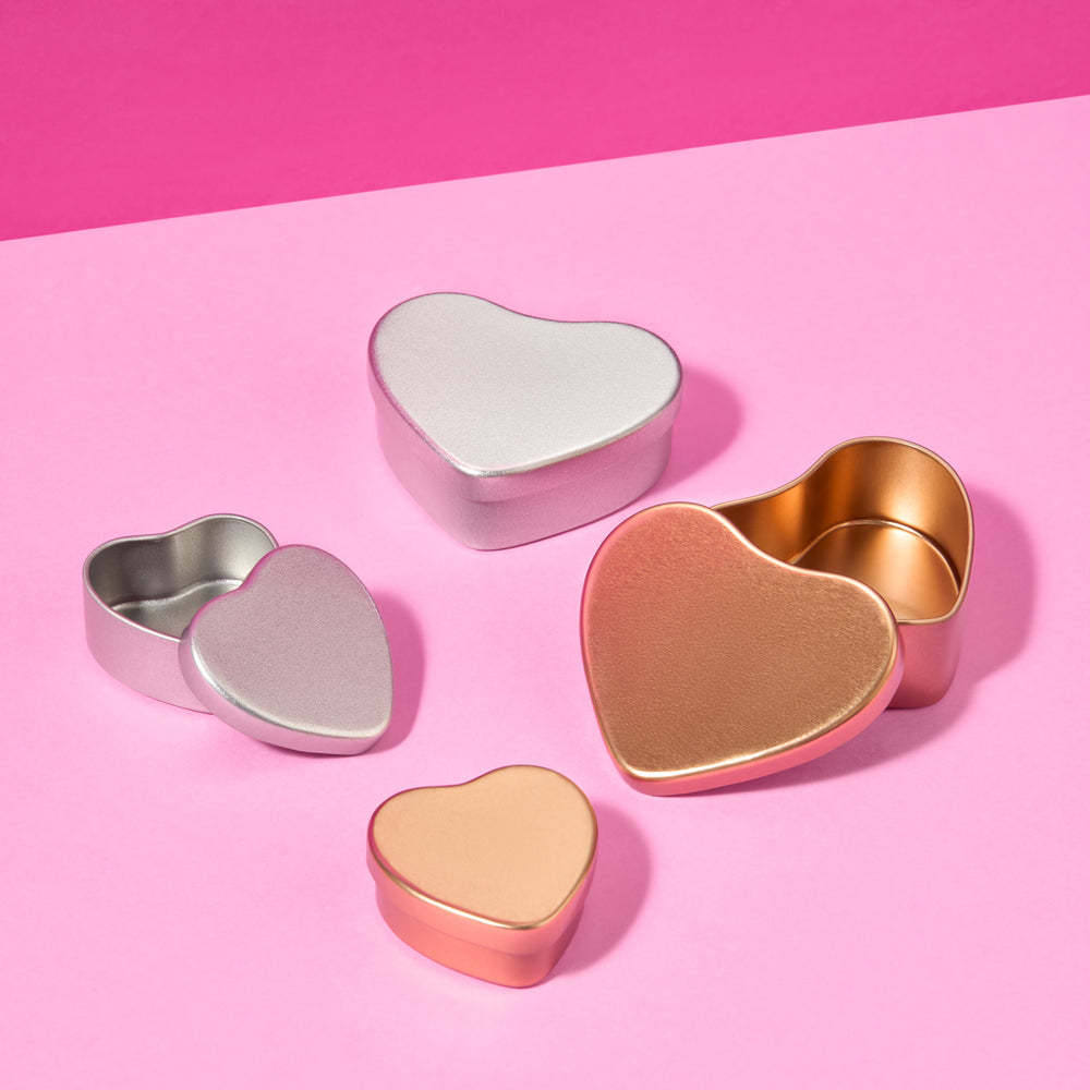 Collection of rose gold and silver tins on pink background